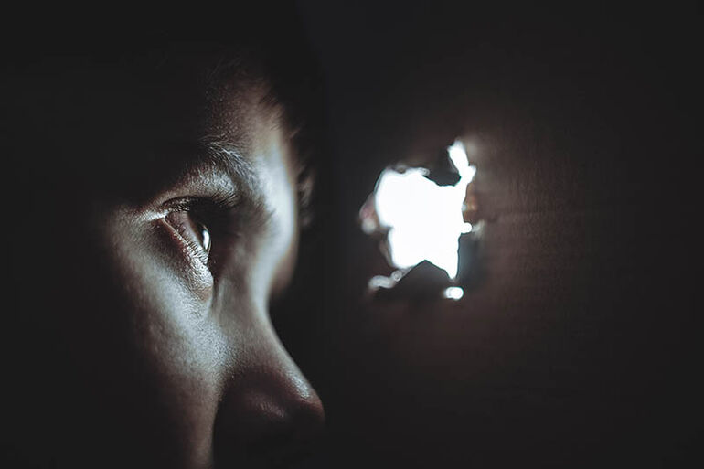 Young boy looking through spyhole - Cookiebot