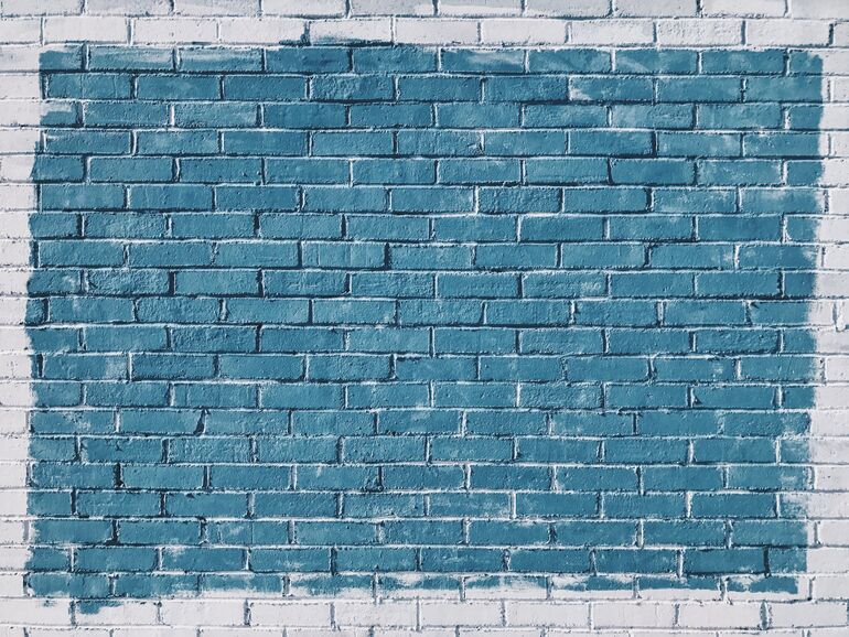 White brick wall with a blue square painted on it - Cookiebot
