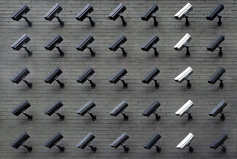 Rows of surveillance cameras on a brick wall - Cookiebot