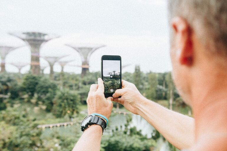 Man taking a photo of the Gardens by the Bay in Singapore on his phone - Cookiebot